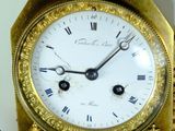 a gold clock sitting on top of a wooden table