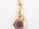 an image of a gold charm with a purple stone in the center