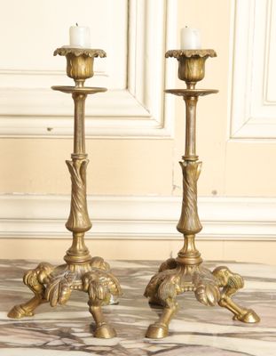 pair of antique brass candlesticks on a marble floor
