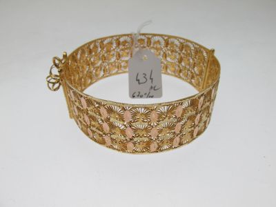 gros plan d'un bracelet en or sur une surface blanche
