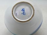 un vase blanc orné d'une inscription bleue, posé sur une table