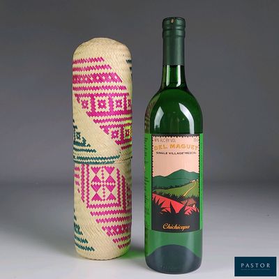 bottles of wine are next to a woven bottle cover on a table