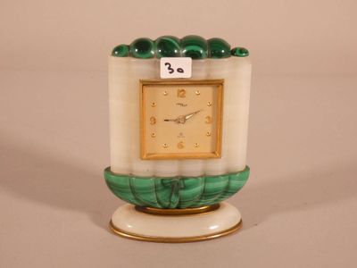 a green and white clock sitting on top of a white pedestal