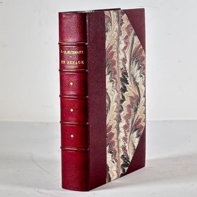 an old red book sitting on top of a table next to a white wall