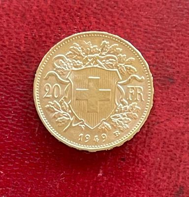 une pièce d'or sur laquelle figure un blason, sur un fond rouge