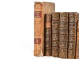 several old books are stacked on top of each other on a white surface