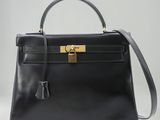 un sac à main en cuir noir muni d'un fermoir doré sur la poignée