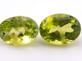 a pair of two green gems sitting on top of a white surface