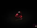 un gros plan d'un diamant rouge en forme de cœur sur une surface noire