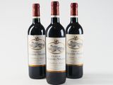 three bottles of red wine sitting on top of a white table