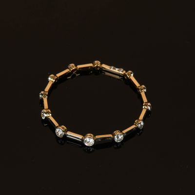 un gros plan d'un bracelet en or et diamants posé sur une surface noire