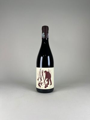 the bottle of red wine is sitting on a white surface