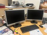 two computer monitors sitting on a desk next to each other