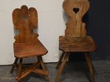 pair of wooden chairs with heart shaped backrests against a white wall