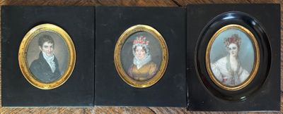 two framed portraits of a man and a woman on a wooden table