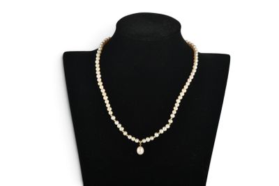 a white pearl necklace with a gold clasp on a black mannequin
