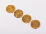 four gold coins are arranged in a row on a white surface