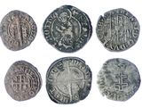six silver coins of different shapes and sizes on a white background