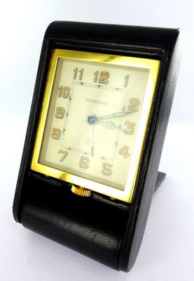 une petite horloge noire avec un cadran jaune sur un fond blanc