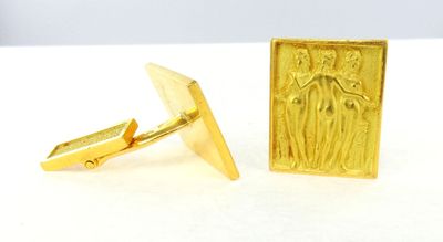 two gold cufflinks with a picture of a man and a woman on them