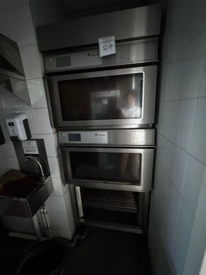 trois fours dans une petite cuisine, avec une poubelle devant eux