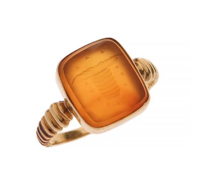 une image représentant une bague en or avec une pierre orange au centre