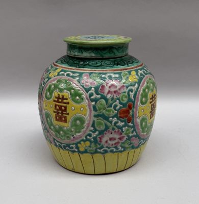 un vase vert et jaune posé sur une surface blanche
