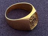 a close up of a gold signet ring on a purple surface