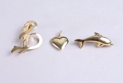 two gold dolphins and a heart charm on a white background
