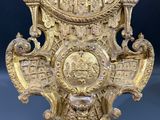 une image représentant une horloge dorée posée sur un socle, sur un fond bleu