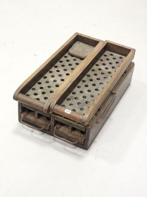 une petite boîte en bois percée de trous, posée sur une surface blanche