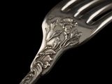 a silver fork with a floral design on it