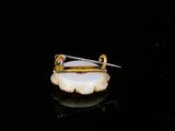 an image of a gold and white broochle pin with a pair of scissors