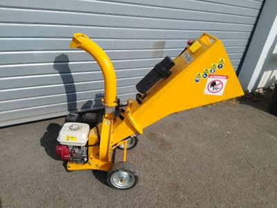 an image of a small wood chipper parked in front of a garage