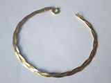 a close up of a gold bracelet on a white surface