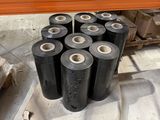 de nombreux rouleaux de plastique noir posés sur une étagère dans un entrepôt