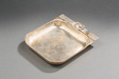 une vieille assiette en argent avec un manche en métal sur un fond gris