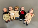 several old dolls are lined up in a row on a gray surface