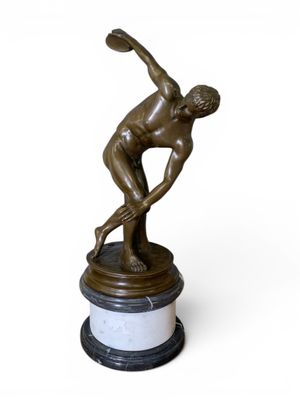 statue en bronze représentant un homme tenant un frisbee, posée sur un socle en marbre