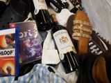 bottles of wine, shoes, and a dvd sit in a suitcase