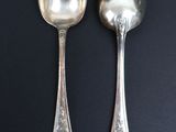 two silver spoons on a black table with a black background