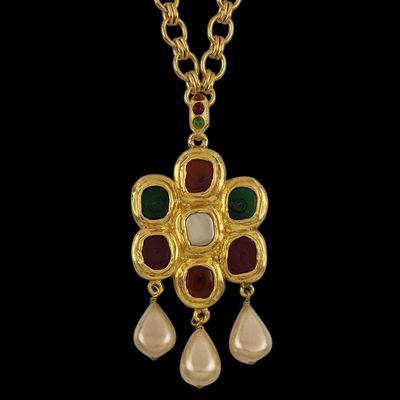 a close up of a necklace with pearls and a gold chain
