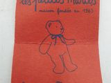a small red teddy bear sitting on top of a piece of paper
