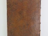 an old book with a brown cover sitting on top of a white surface