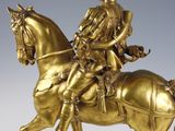 bronze statue of a man on a horse holding a flag