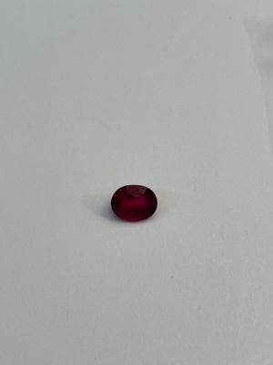 a red stone sitting on a white surface in the snow