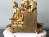 a gold figurine of a boy and a rooster on a bench