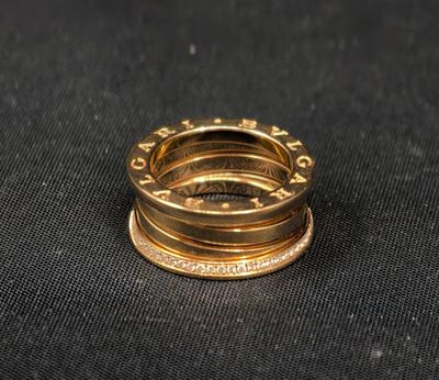 un gros plan d'une bague en or posée sur un tissu noir