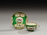 une tasse et une soucoupe vertes et dorées ornées d'un oiseau