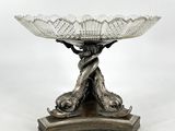 un plat ancien en argent orné d'un oiseau, posé sur un socle